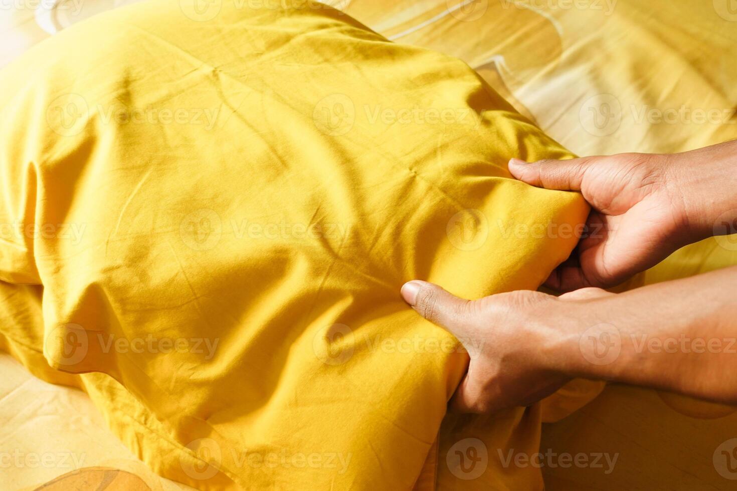 Preparing a yellow pillow for a cozy bed setup photo