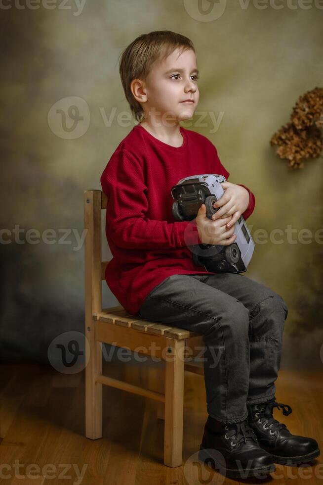 A boy sitting on a chair holding a camera photo