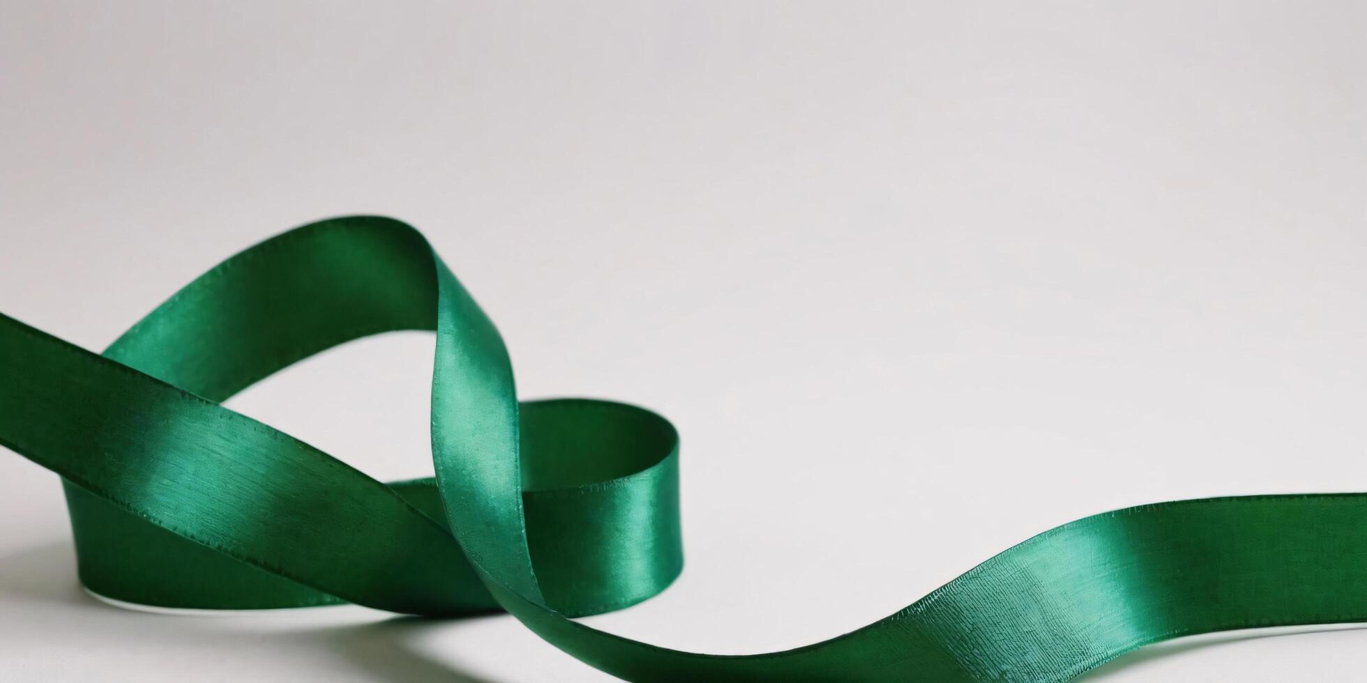Emerald green satin ribbon elegantly curled on white background. photo
