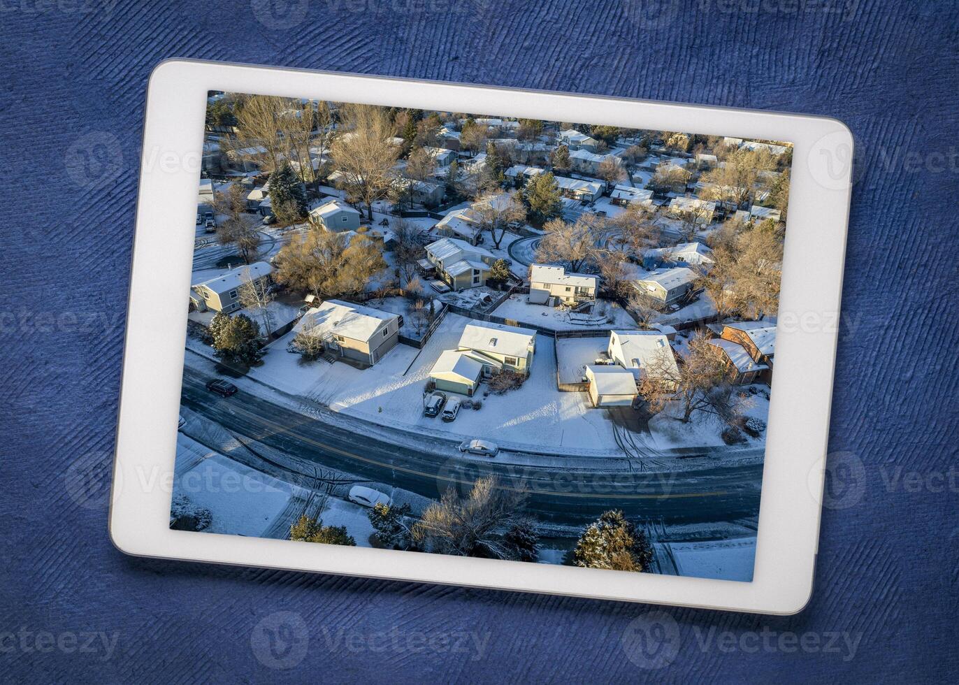 winter morning over a residential area of Fort Collins in northern Colorado with fresh snow, reviewing aerial image on a digital tablet photo