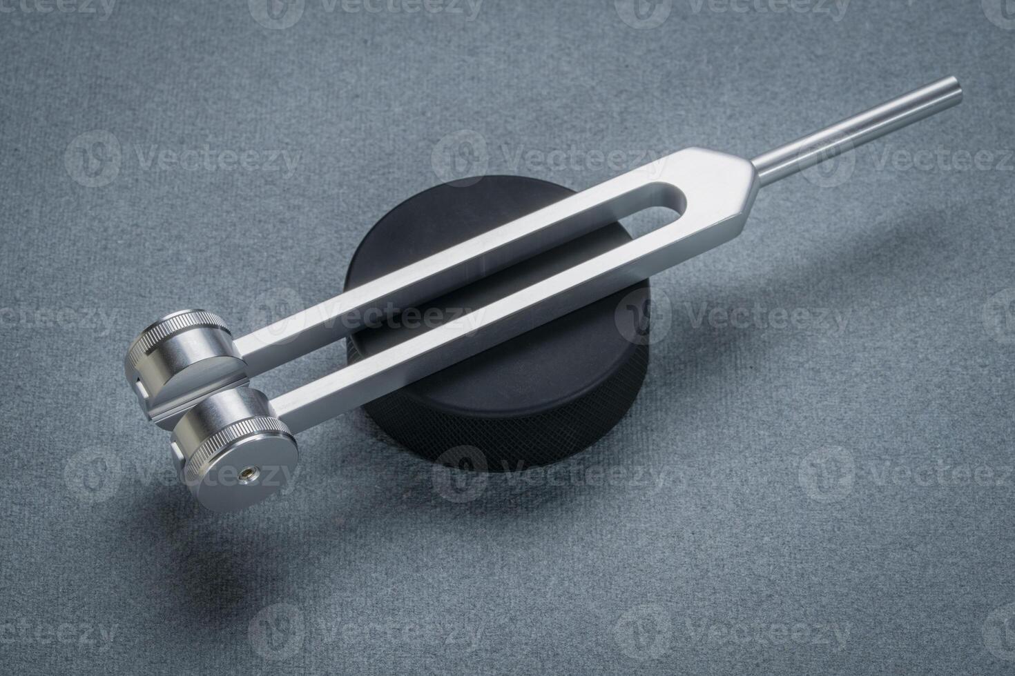 Metal weighted tuning fork used for tuning musical instruments, sound therapy, chakra healing or relaxation, hockey puck actovator. photo