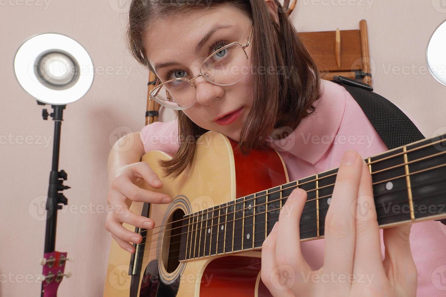 Closeup of woman guitarist playing acoustic guitar, singing song as she plucks strings with emotion photo