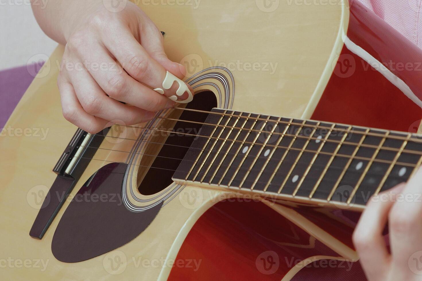 Close-up view of female guitarist is performing captivating solo, deftly manipulating fingers over frets and neck of acoustic guitar. This performance, executed in strumming style with guitar pick photo
