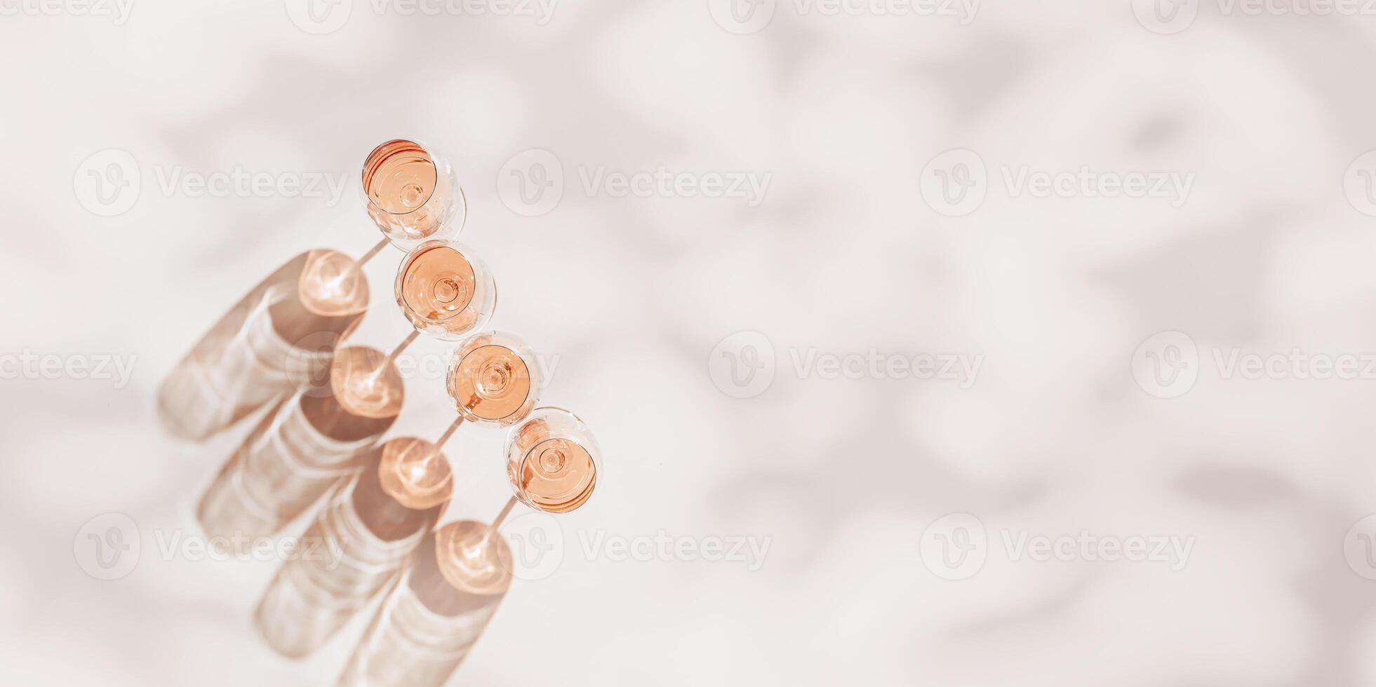 Rose wine glasses Minimal flat lay. Holiday aesthetic still life, top view wineglass at sunlight, plant leaves sun shadow, monochrome beige pink pastel color, drink background, copyspace, banner photo
