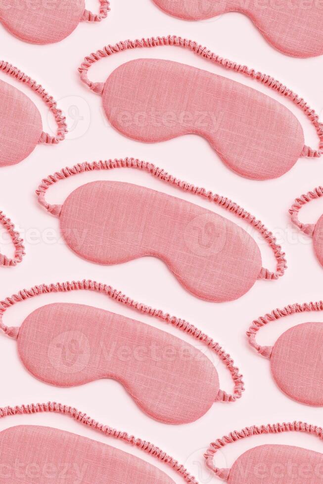 Minimal style pattern from pink sleep masks on pink background. Trend Colored fashion eye masks for best sleeper, for travel, comfort rest. Night time and sleep concept, vertical flat lay photo