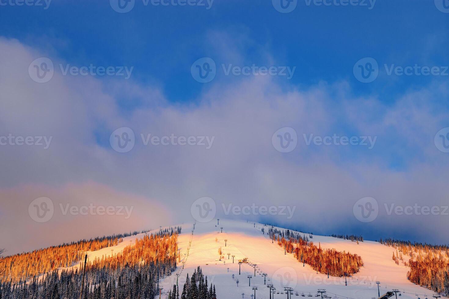 Picturesque sunrise and winter mount covered snow and forest, pink clouds on sky, white snow slopes and ski traces, view on mountain Green mount Zelenaya, Sheregesh ski resort in Russia photo
