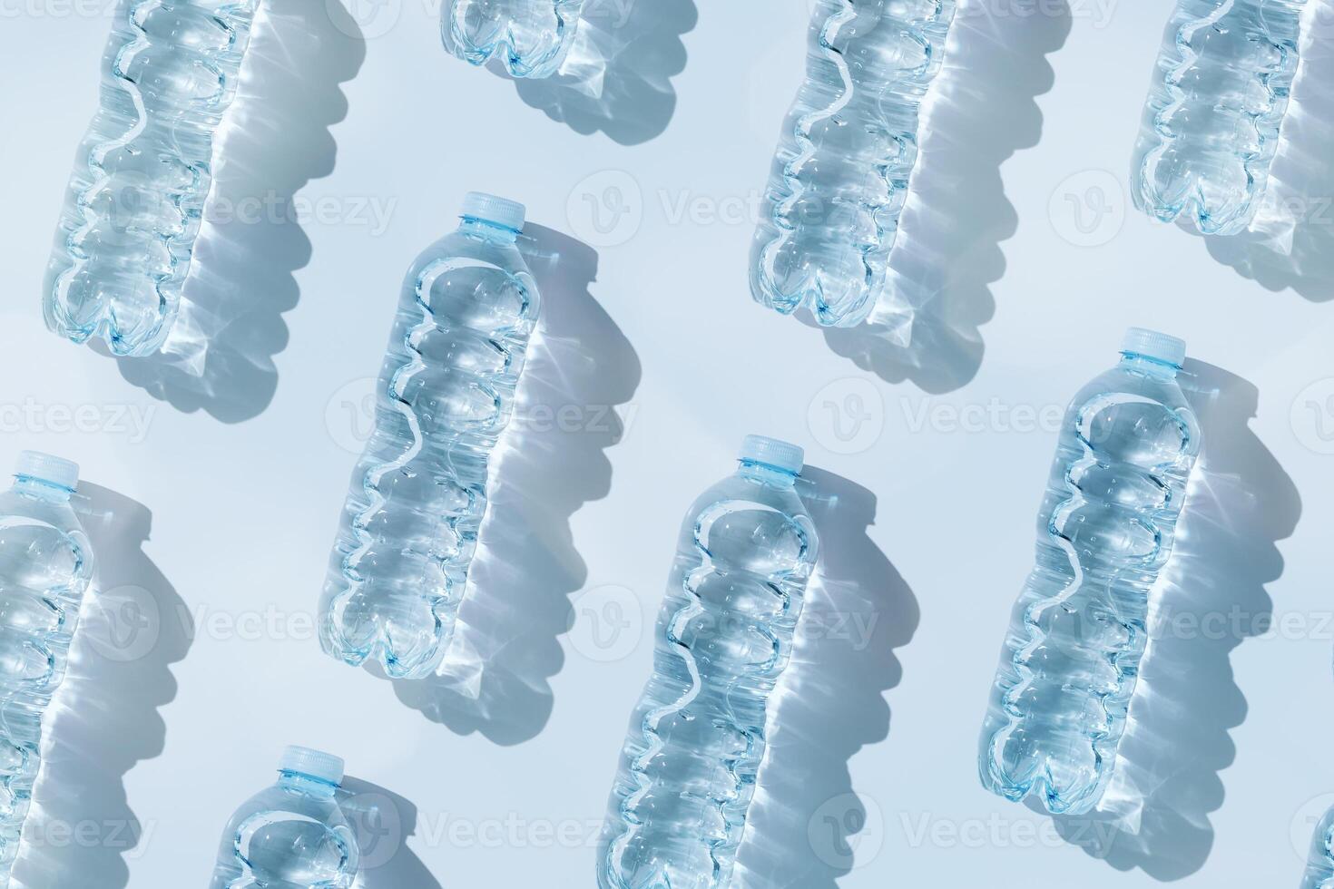 Minimal Pattern Plastic bottles water at sunlight with shadow on blue, aesthetic top view. Distilled drinking water. Pollution, environmental protection. Eco trend to reduce disposable plastic photo