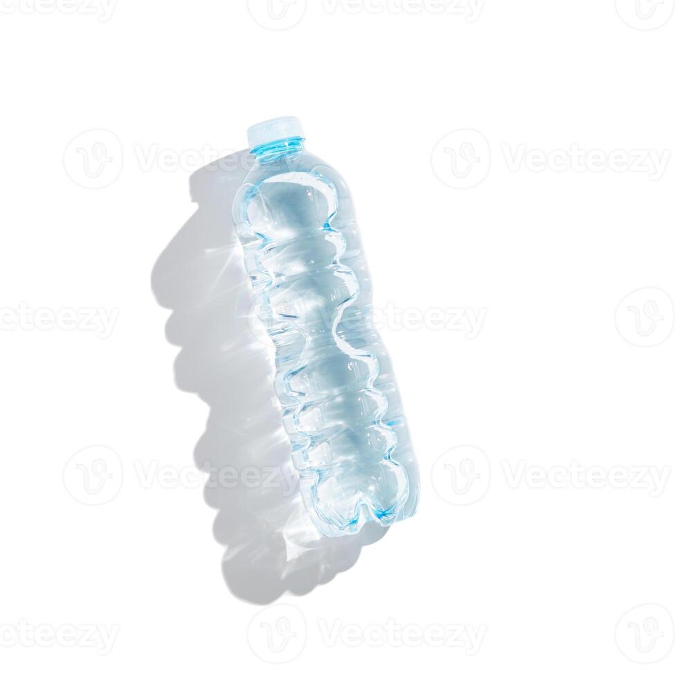 Plastic bottle water at sunlight with beautiful sun shadow isolated on white background, cut out object. Clean drinking water half litre in Small closed full bottle, non-biodegradable packaging photo