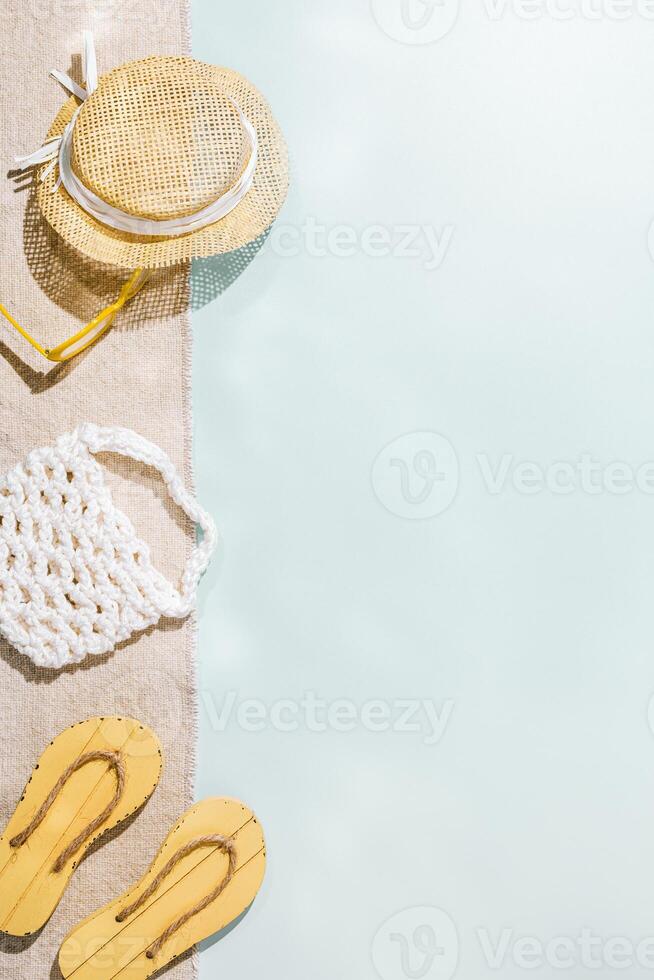 Summer flat lay with sunglasses, sun hat, white bag, beach shoes flip flops, top view on light green blue background, copyspace. Summer rest vibes, beach relaxation, life style vacation photo