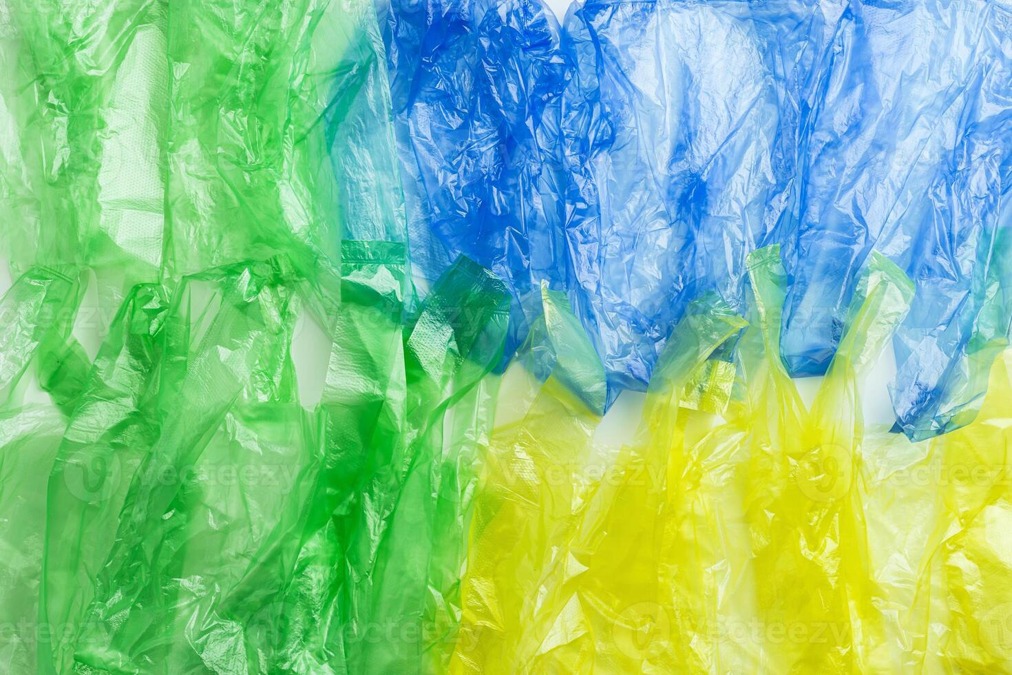 Plastic bags texture, top view crumpled plastic bag crumpled, green blue yellow colored textured background. Surface from Disposable polythene packet. Reusable materials, packaging waste photo