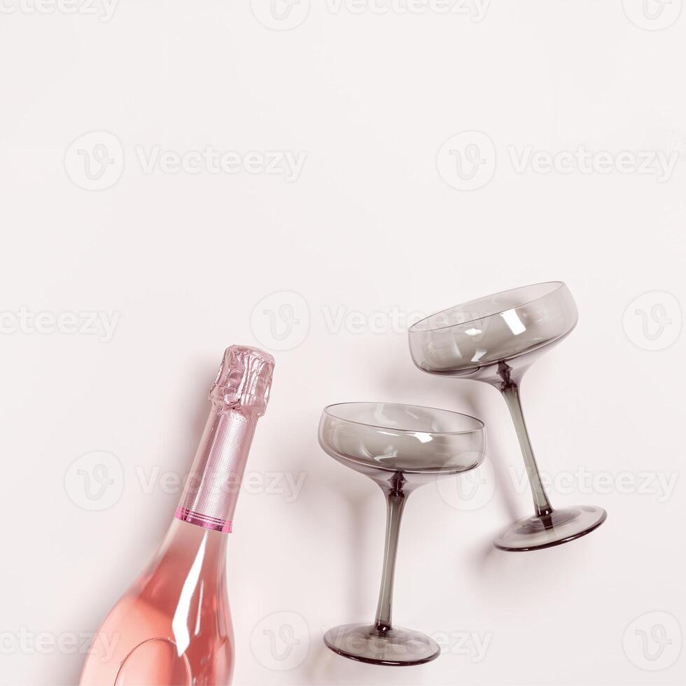 Rose Champagne or sparkling wine bottle, wine glasses grey glass. Romance festive drink concept, glare from sunlight. Modern wine colored glasses. Minimal creative aesthetic flat lay, copy space photo