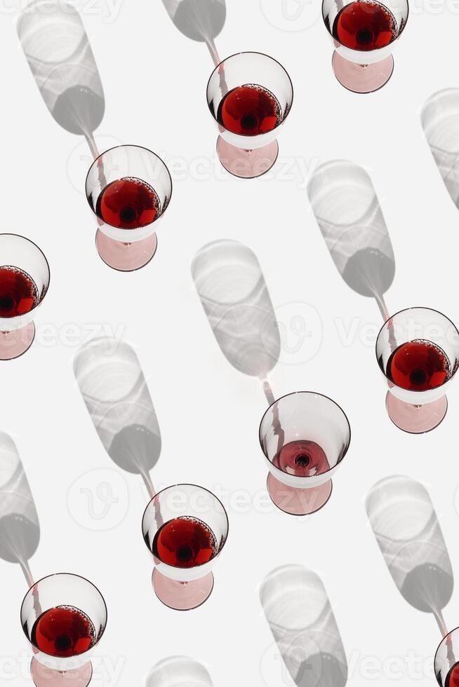 Minimal pattern with glasses of red wine with sunlight shadows, Creative idea summer flat lay with Full Wine glasses and one empty on white, layout alcohol drinks, trend aesthetic photo