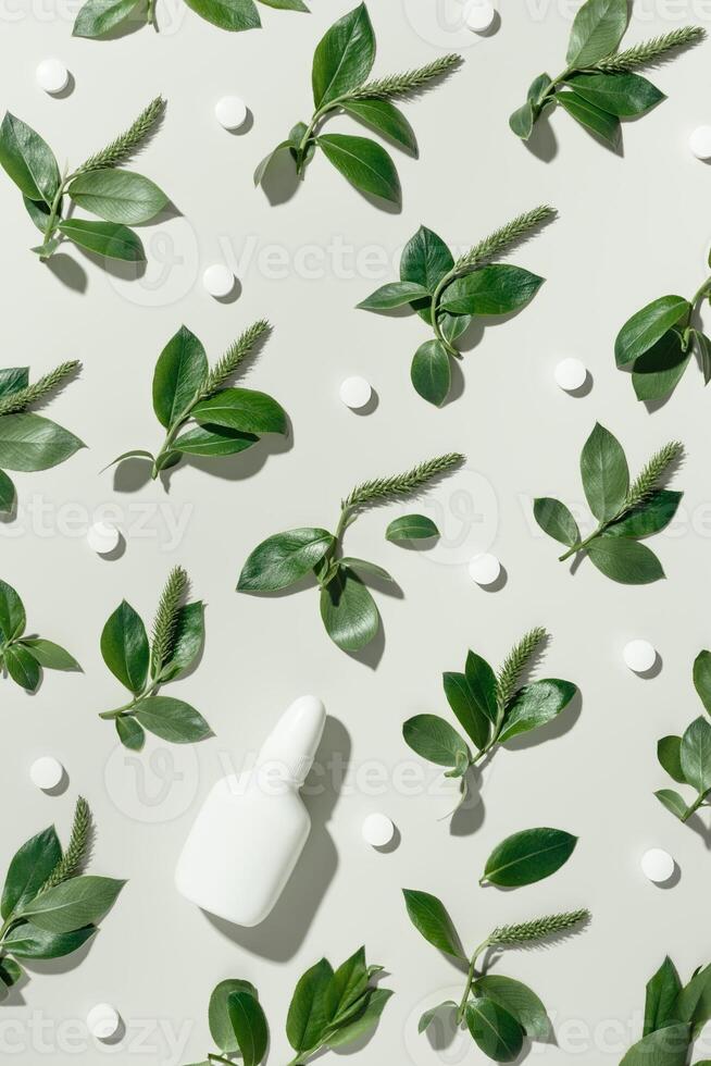 Seasonal spring allergies, fresh spring blooming branches tree with green new leaves, white nasal spray bottle, pills on beige background, top view trend flat lay pattern, Allergy treatment photo
