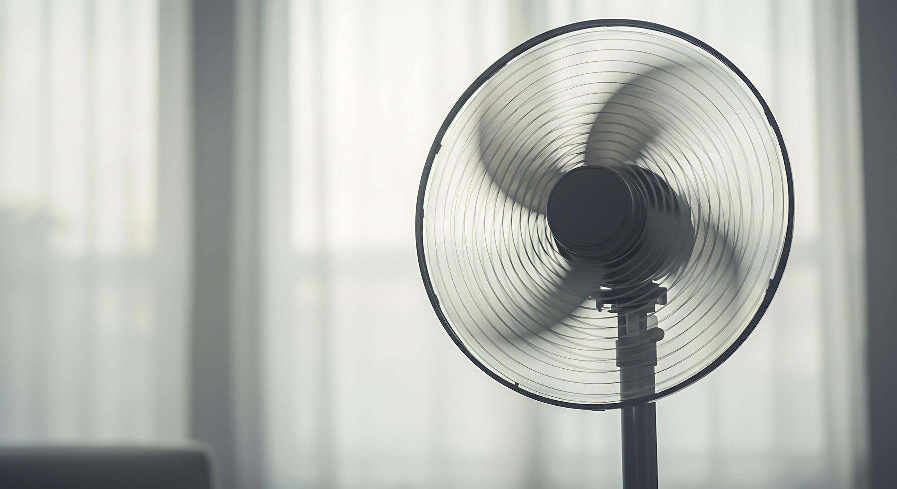 A Modern Stand Fan Circulating Air in a Bright Room Near Sheer Curtains photo