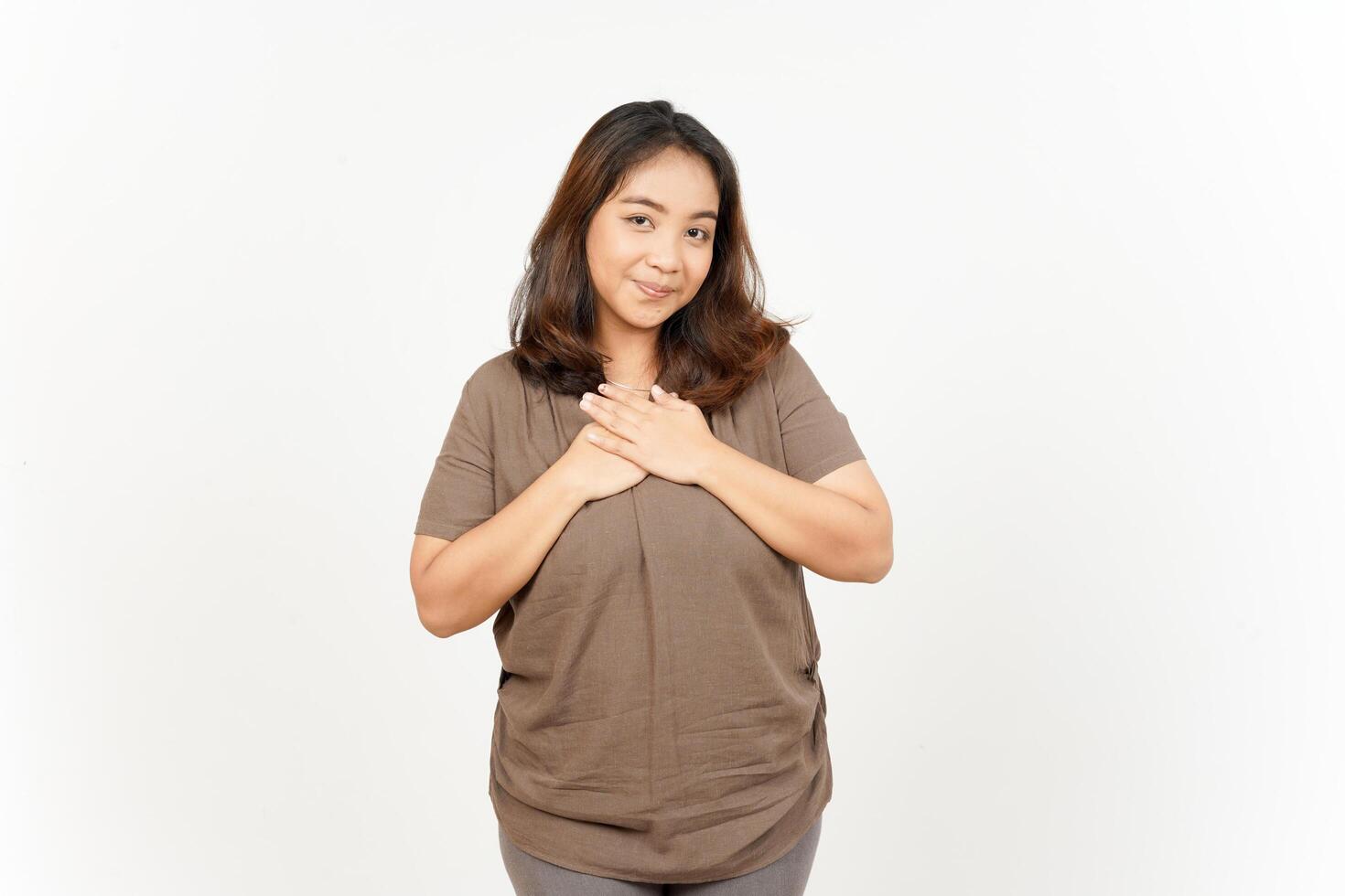 A woman in a brown shirt is holding her chest photo