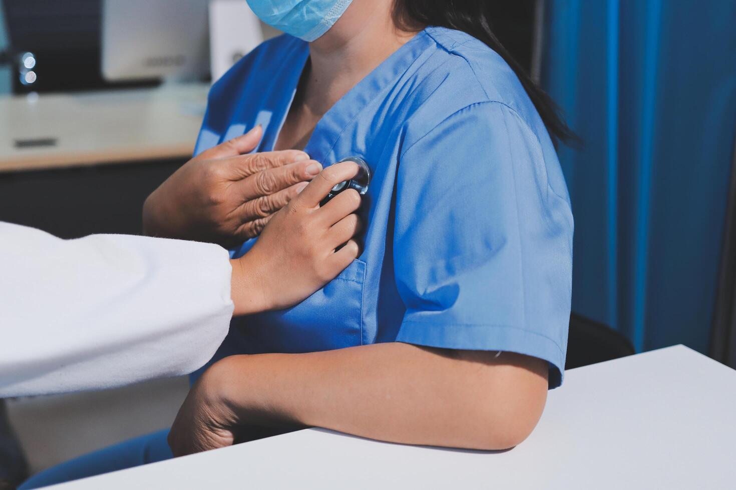A woman in a blue scrub suit is putting on a mask photo