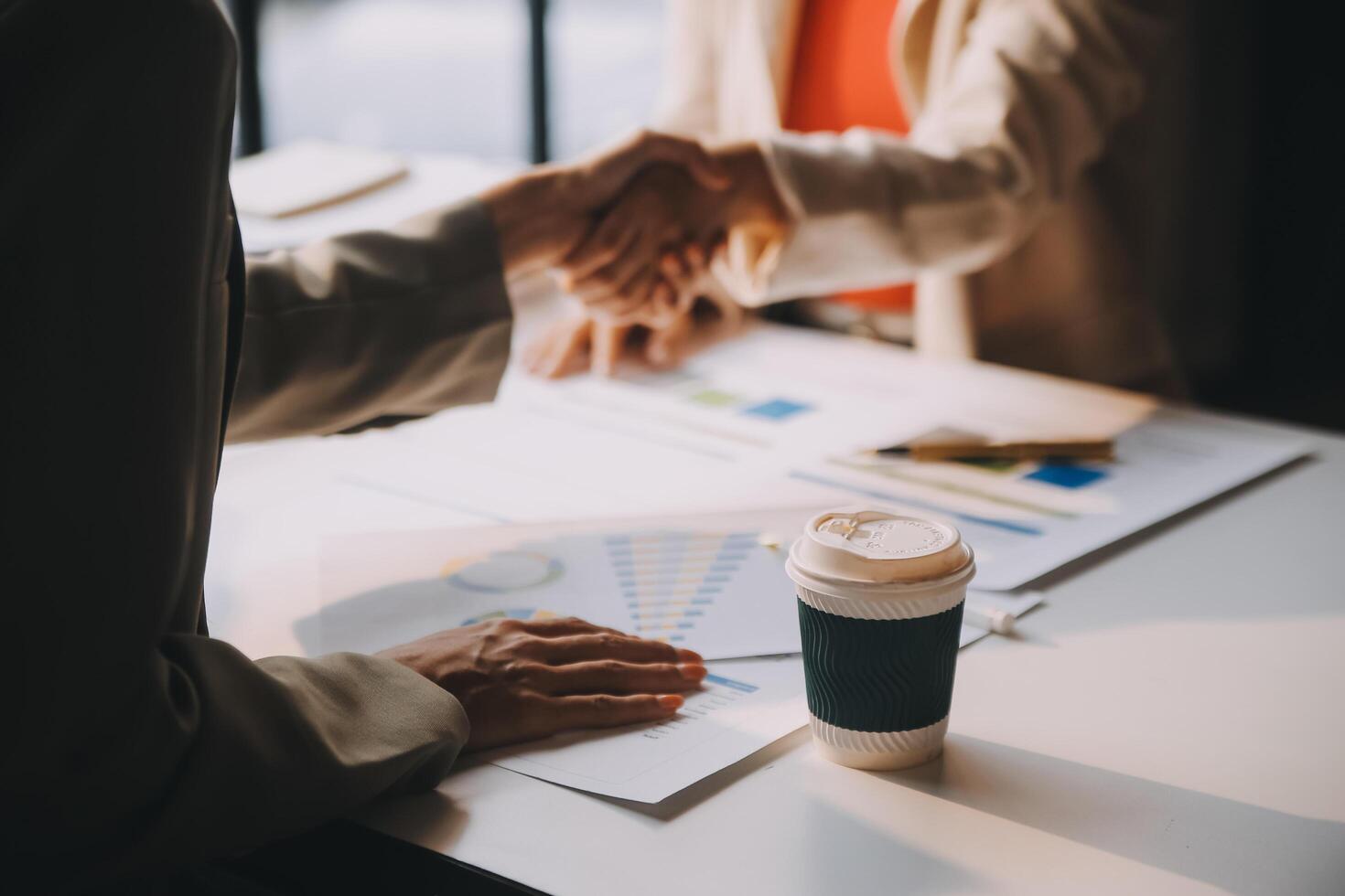 Business people shaking hands over a table with coffee photo