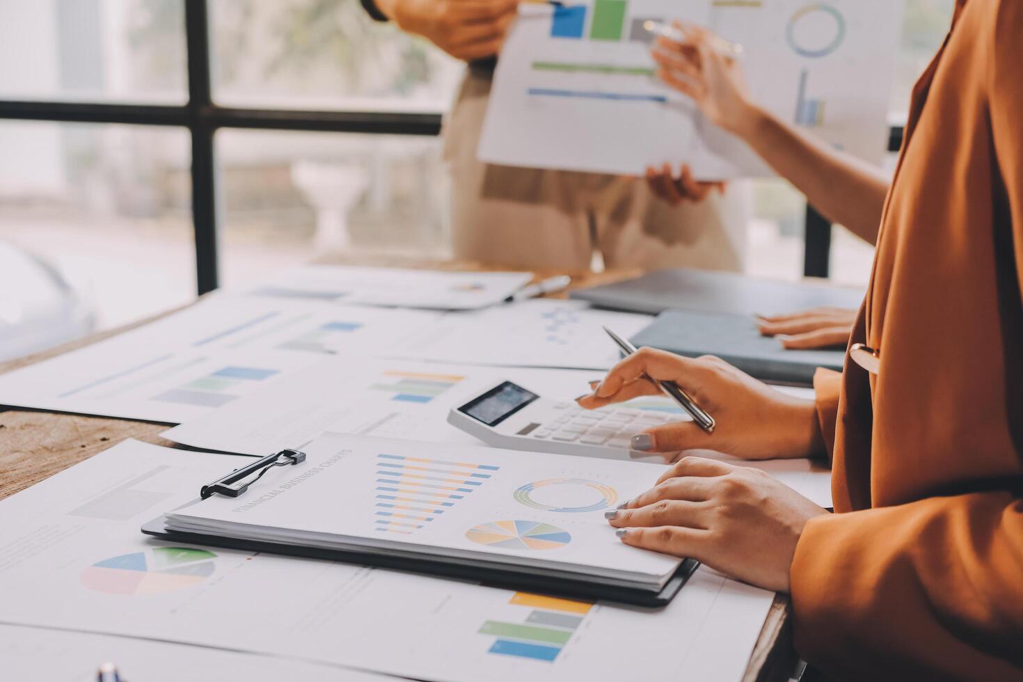 Business people working on graphs and papers at a table photo