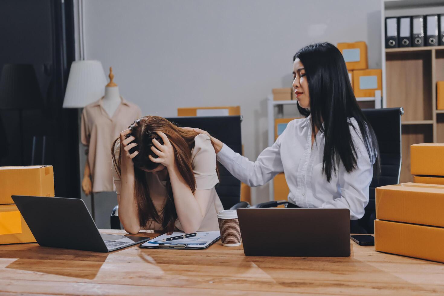 Two women sitting at a desk with laptops photo