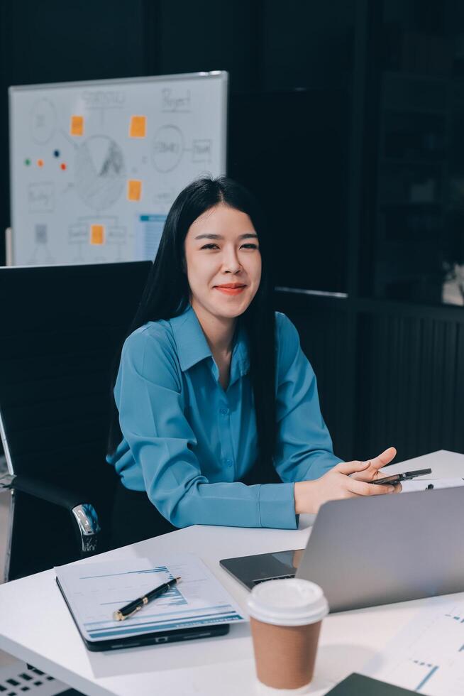 Asian businesswoman sitting at desk with laptop photo