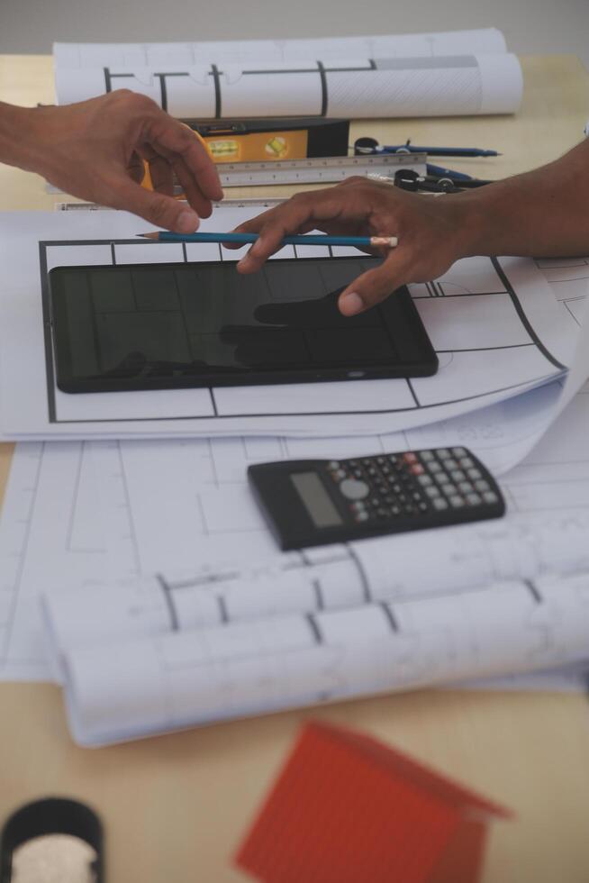 A person is using a tablet on a table with blueprints photo