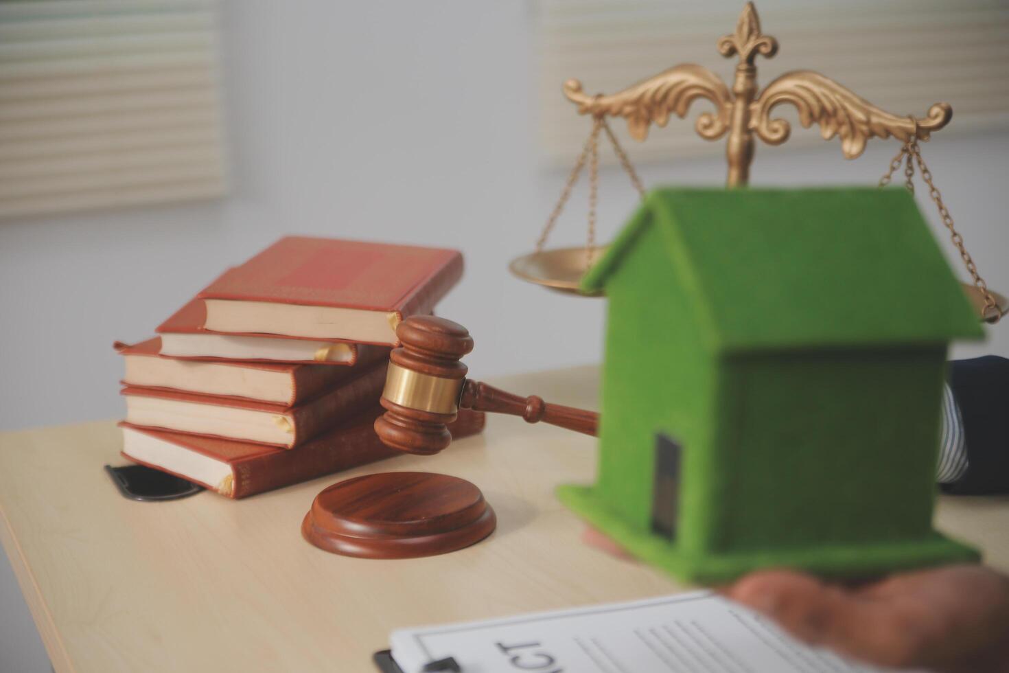 A house model and a gavel on a desk with books and a scale model of a house photo