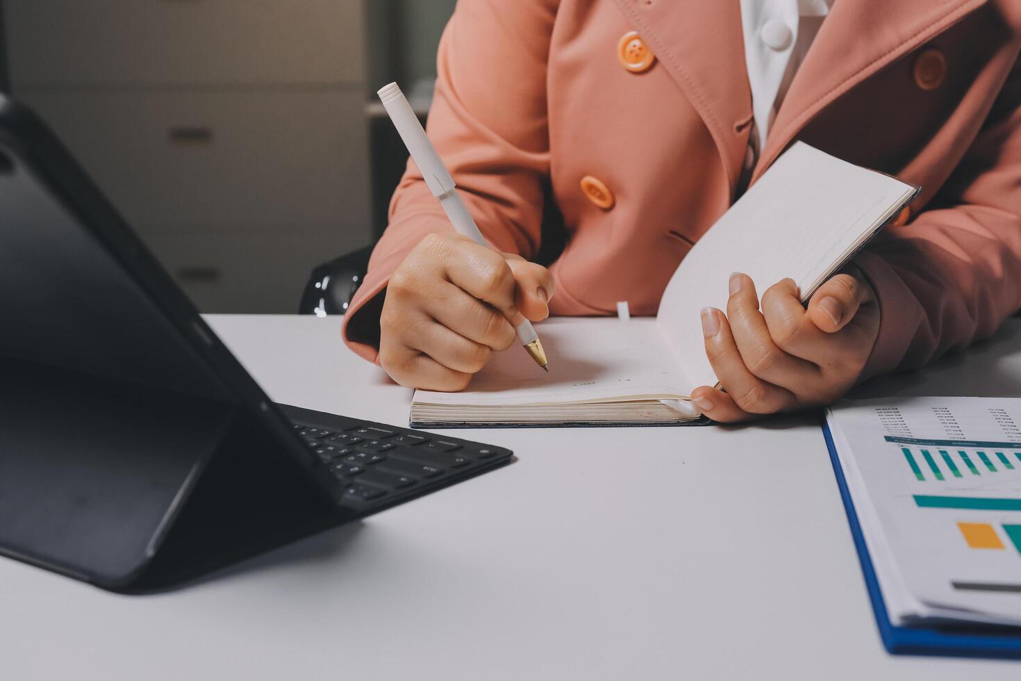 A woman is writing in a notebook while sitting at a desk photo