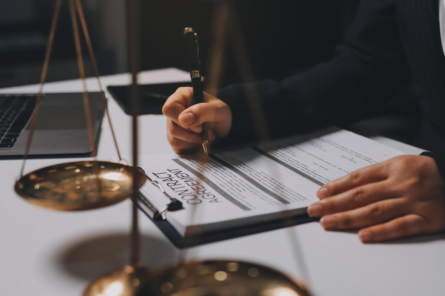 A lawyer signing a document on a desk with a scale of justice photo