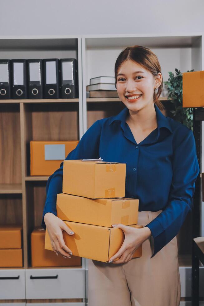 A woman holding a stack of boxes in an office photo