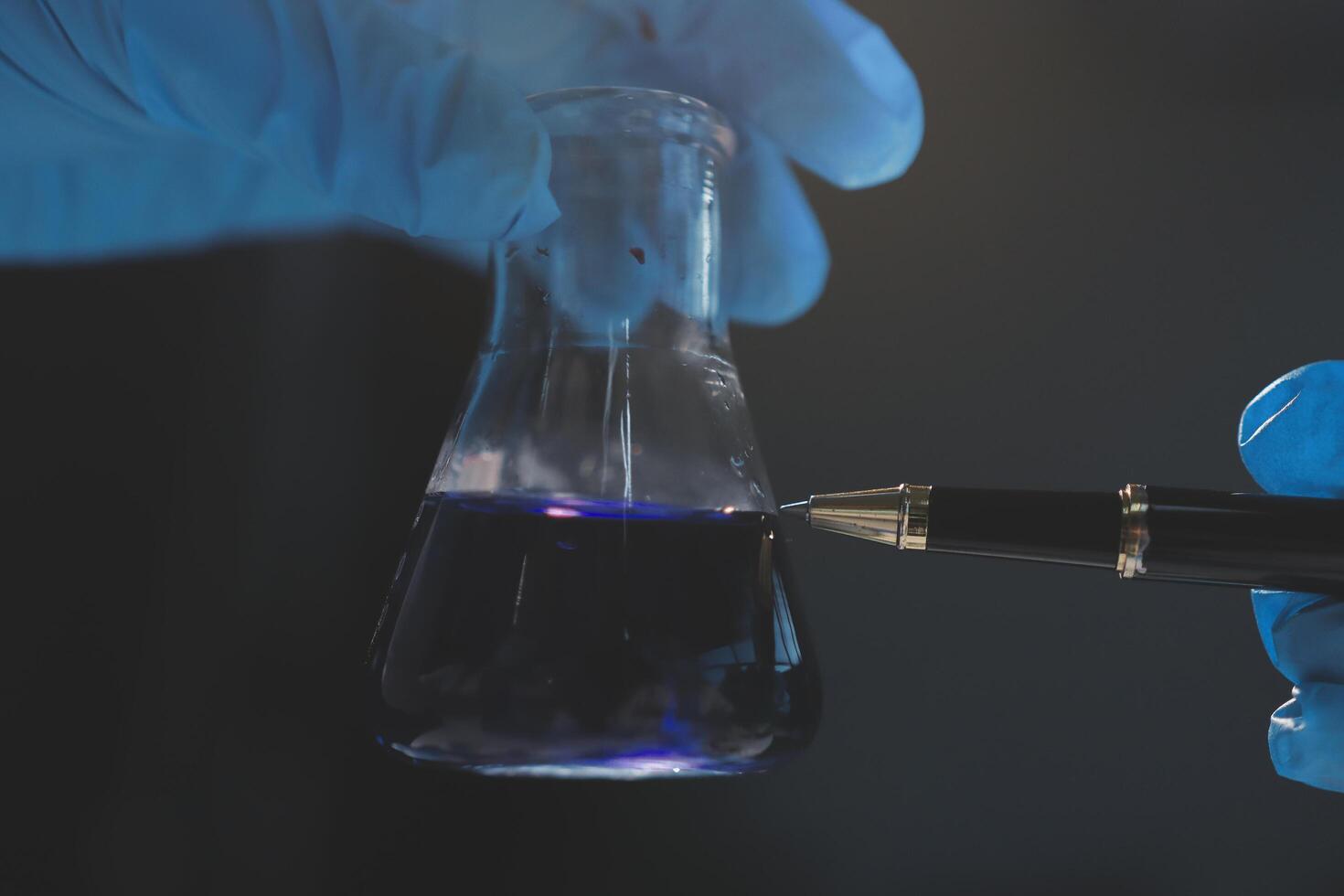 A person in blue gloves holding a pen and a test tube photo