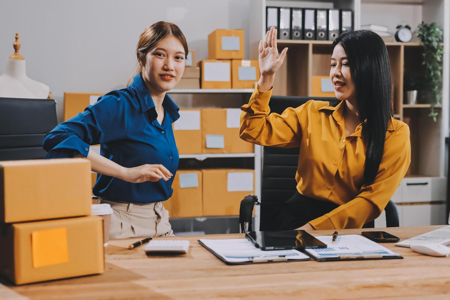 Two women in an office waving at each other photo
