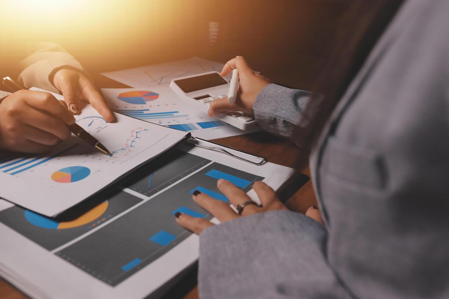 Business people working on a laptop with graphs and papers photo