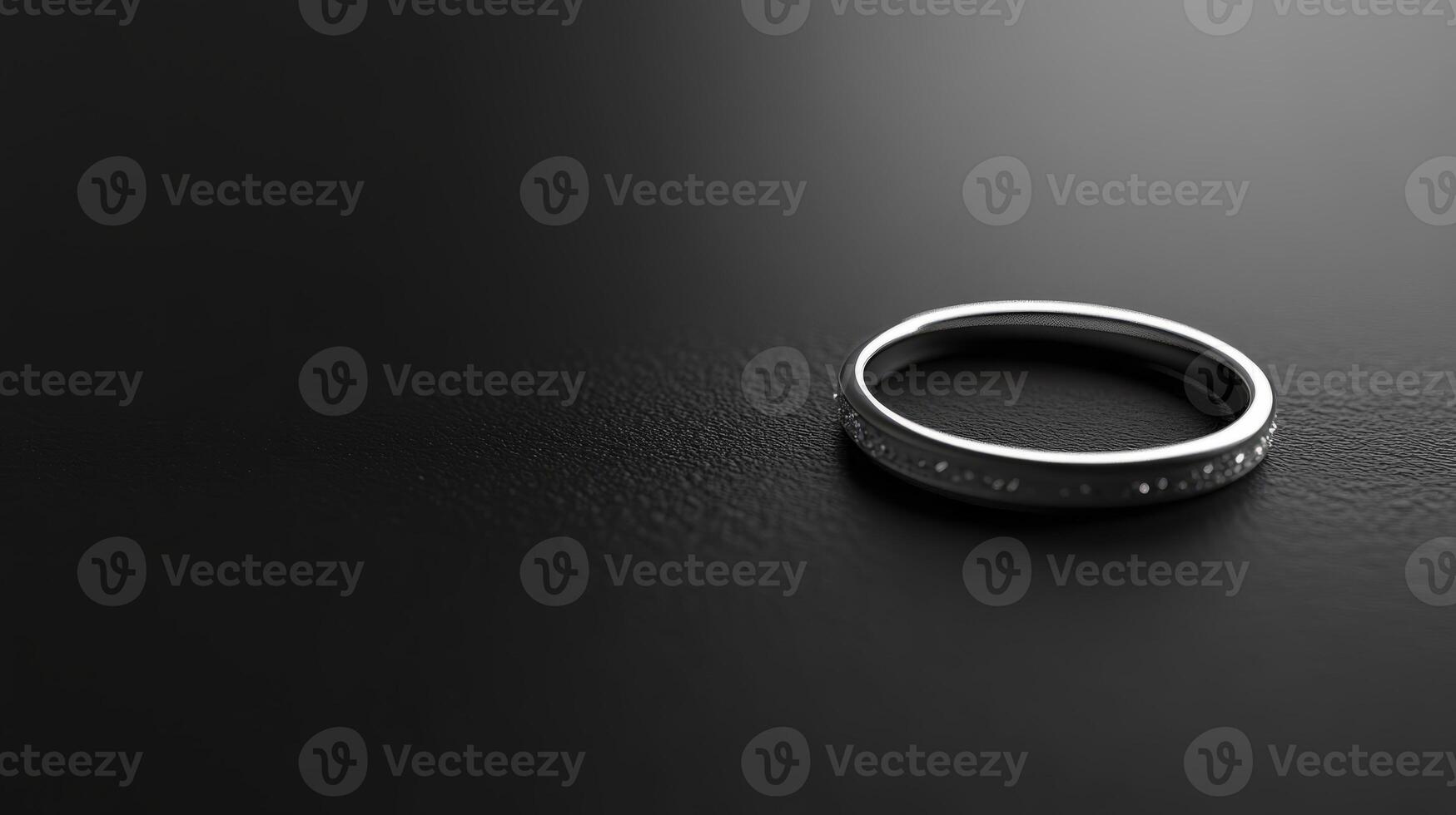 A sleek silver ring displayed on a textured black surface, perfect for showcasing elegance and simplicity in jewelry design. photo