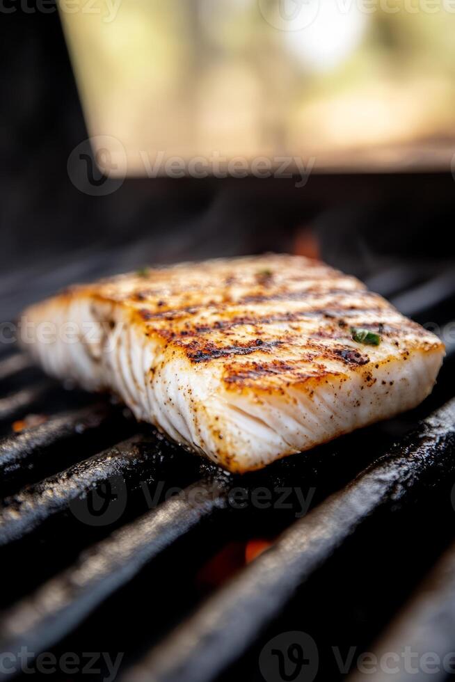 Piece of fish is being grilled on a grill. The fish is brown and has a lot of seasoning on it photo