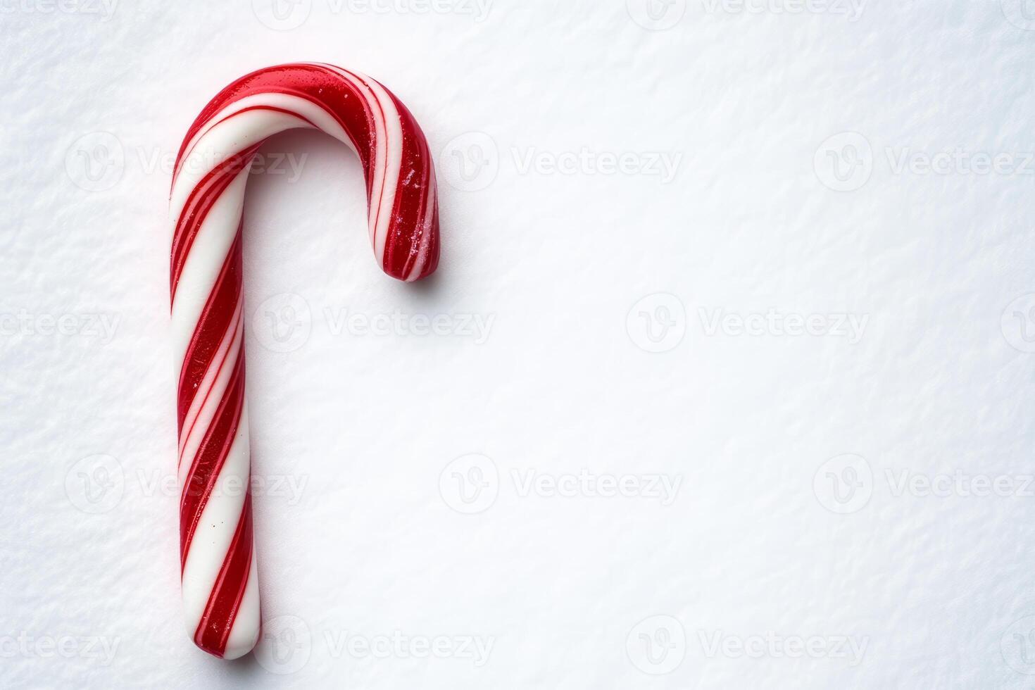 A classic red and white candy cane on a snowy white background, ideal for holiday and Christmas-themed designs and promotions. photo