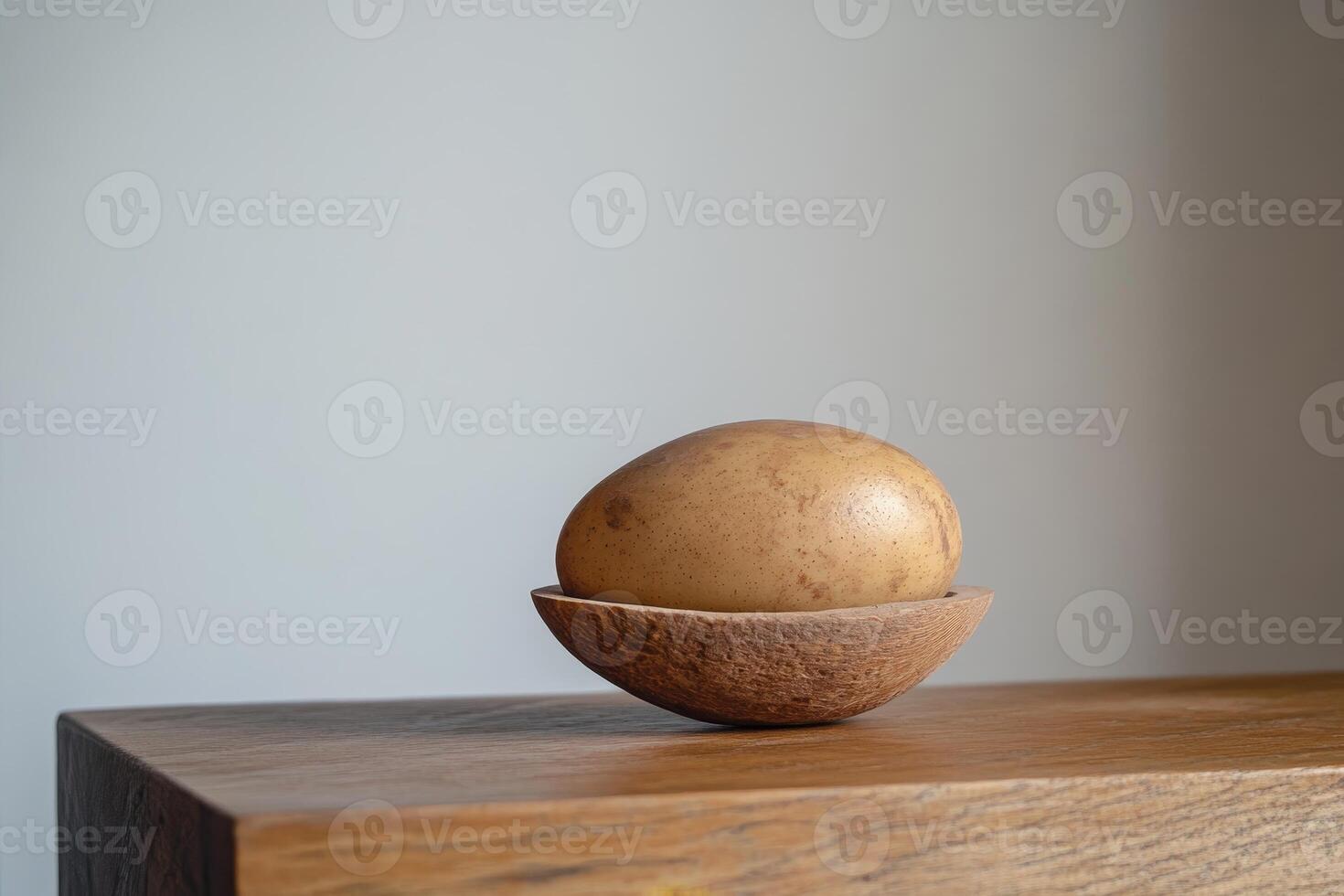 A potato is sitting on a wooden table. The potato is in a bowl, which is on a wooden table photo