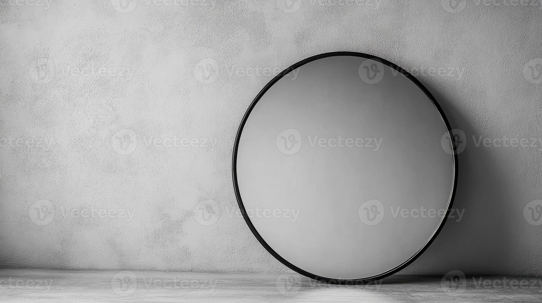 A sleek round mirror leaning against a textured gray wall, showcasing minimalist interior design and contemporary style. photo