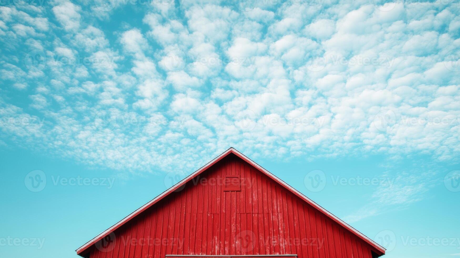 A red barn with a blue sky in the background. The barn is the main focus of the image, and the blue sky in the background creates a sense of calm and serenity photo