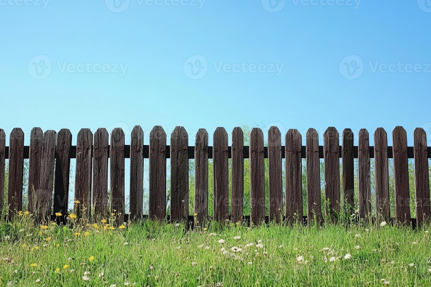 Rustic Wooden Fence with Wildflowers Under Clear Blue Sky in a Serene Countryside Setting photo