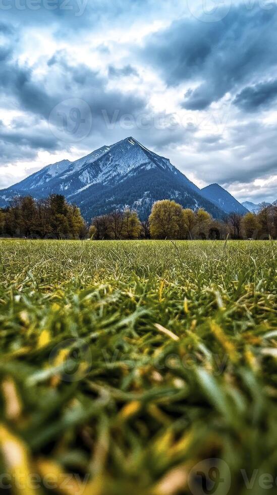 Majestic Mountain Vista A Scenic Landscape Photography Capture Showcasing the Breathtaking Beauty of Nature, Featuring Rolling Green Fields, Lush Trees in Autumn Colors, and a Towering Mountain Peak photo