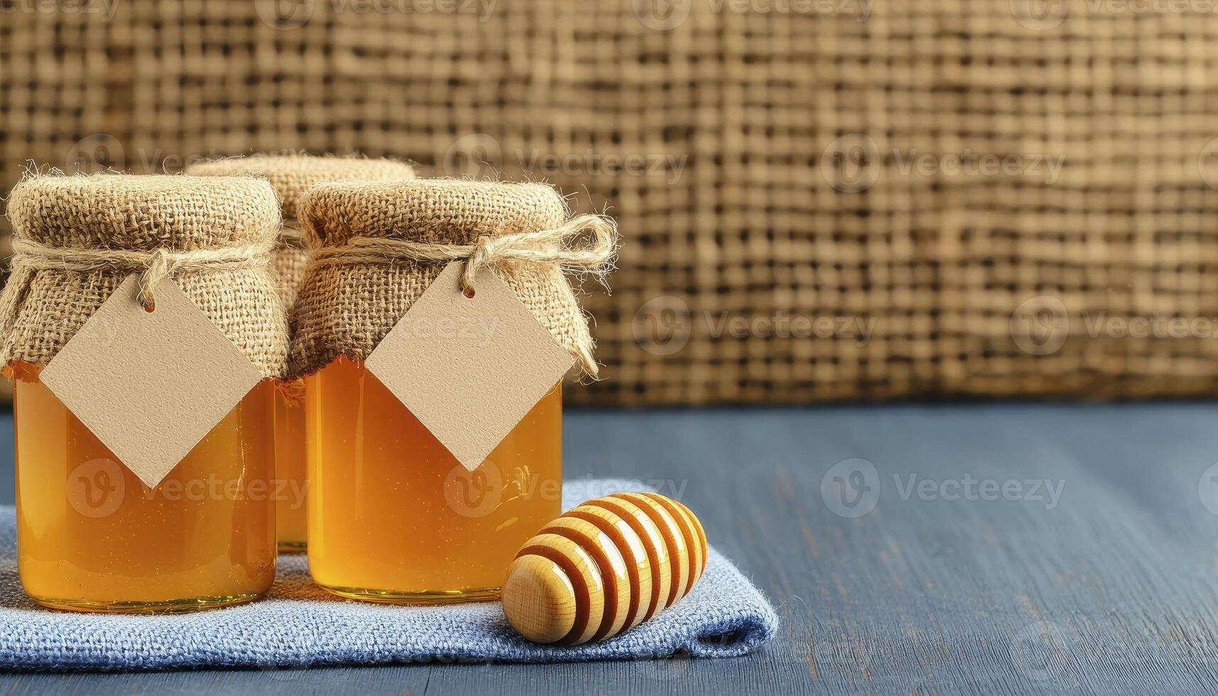 Capture the golden glow of nature's sweetener with this evocative image showcasing three charming jars of honey, each adorned with a rustic burlap lid and a blank label, inviting personalization the photo