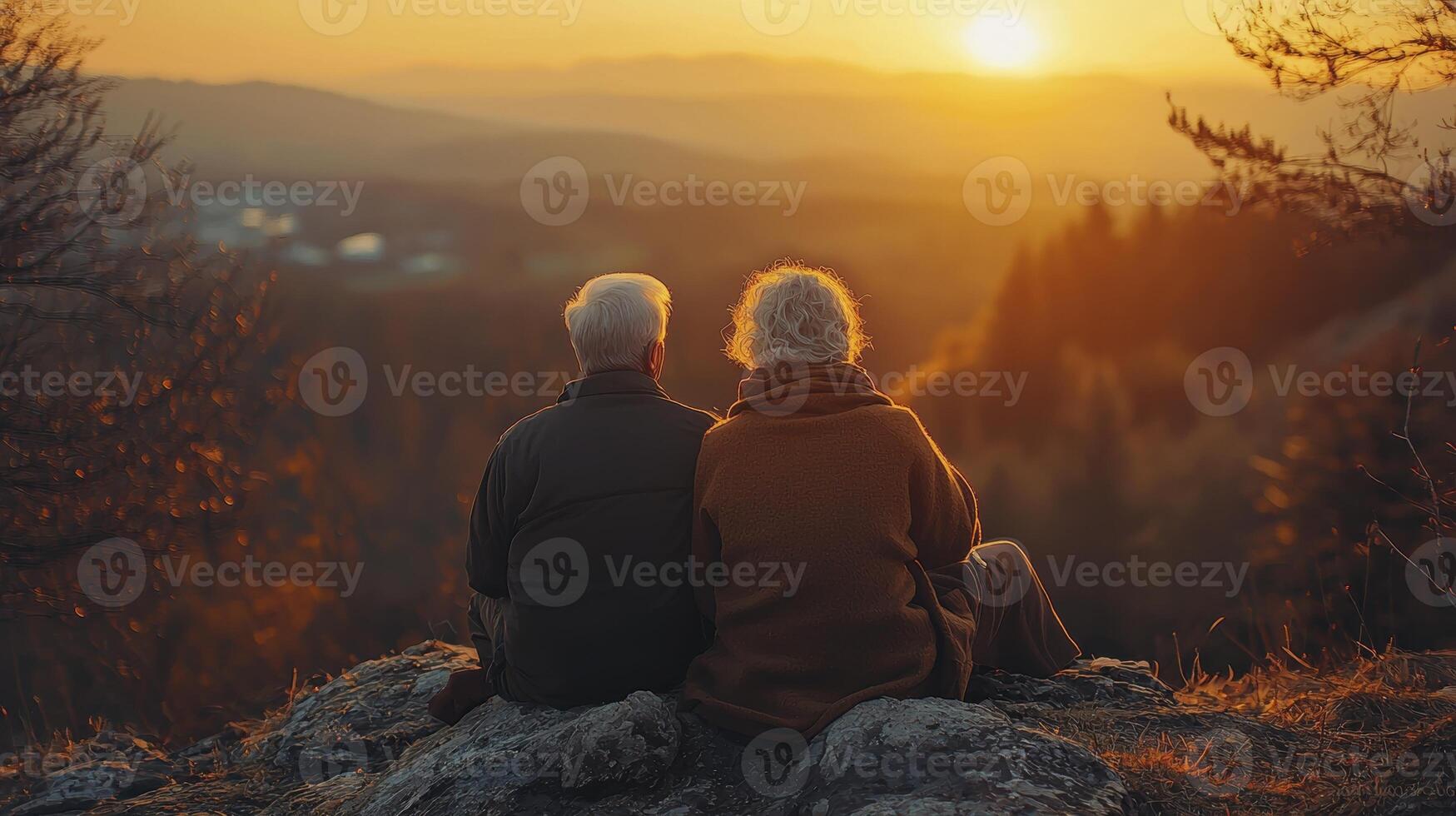 At the summit of life, two souls intertwined, watch a new dawn paint the sky with hues of gold and serenity A senior couple, their silver hair kissed by the first light, share a quiet moment of photo