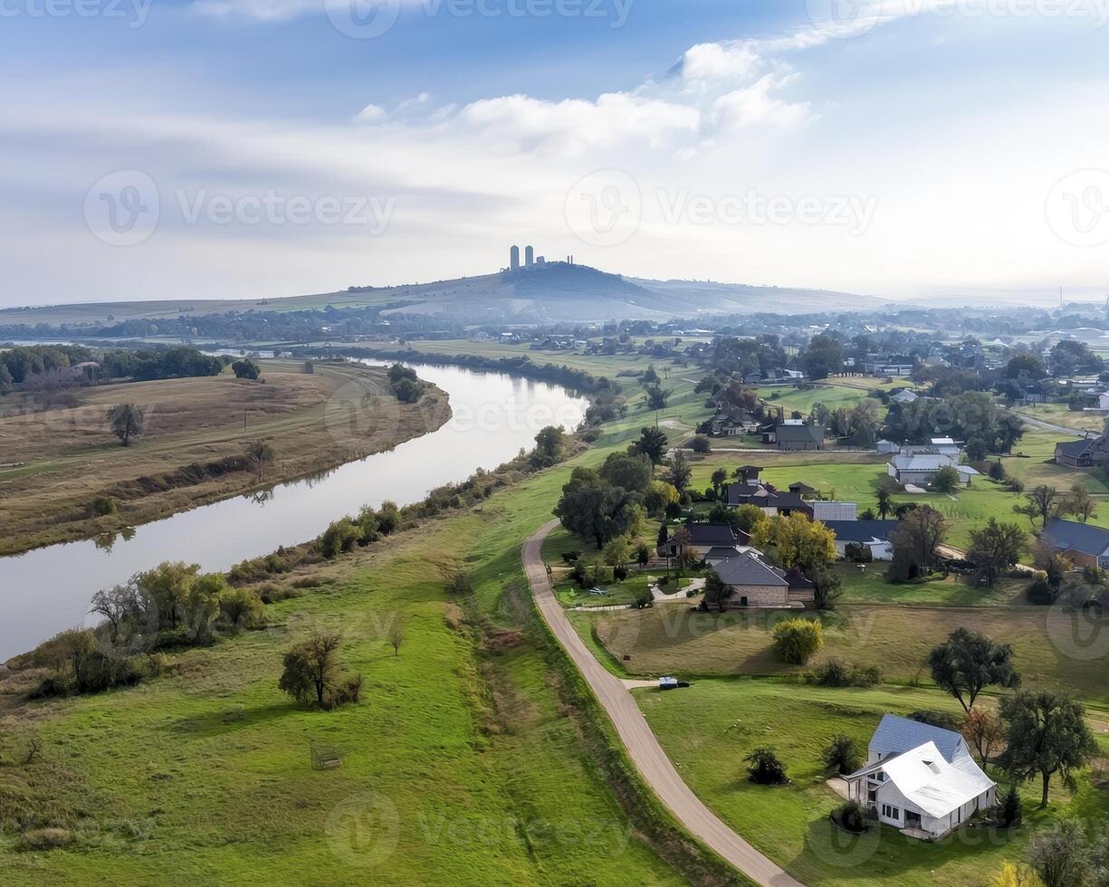 From high above, a river snakes its way through a seemingly limitless expanse of verdant grasslands The water reflects the sky, mirroring the clouds that drift lazily overhead This tranquil scene photo