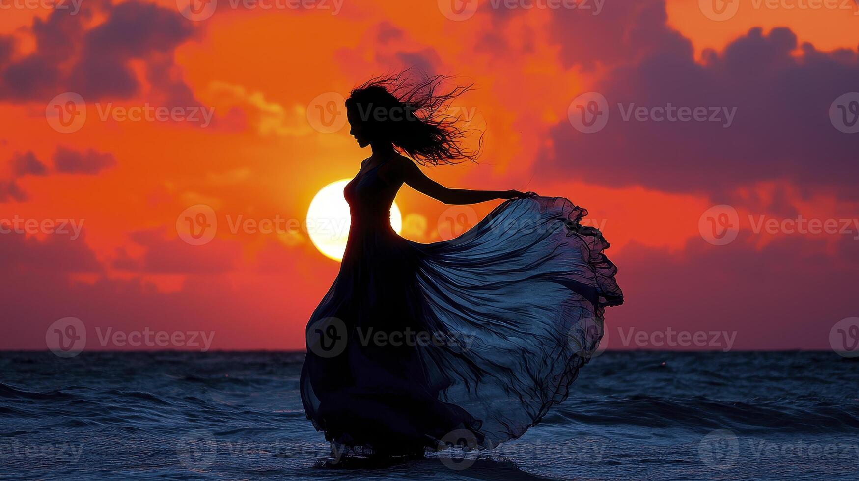 In a serene landscape painted with the fiery hues of sunset, a woman stands as a silhouette, a dark echo against the vibrant sky With arms outstretched, she twirls with unrestrained joy, her dress photo
