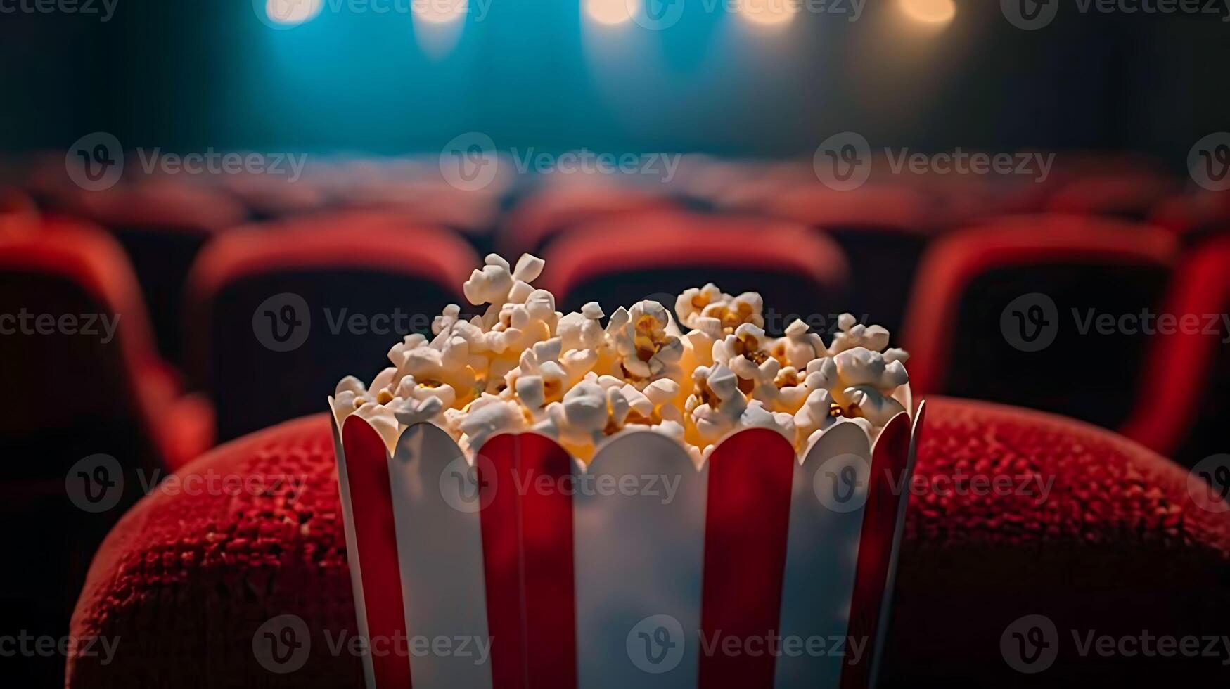 Popcorn in a red and white striped bucket on a red chair photo