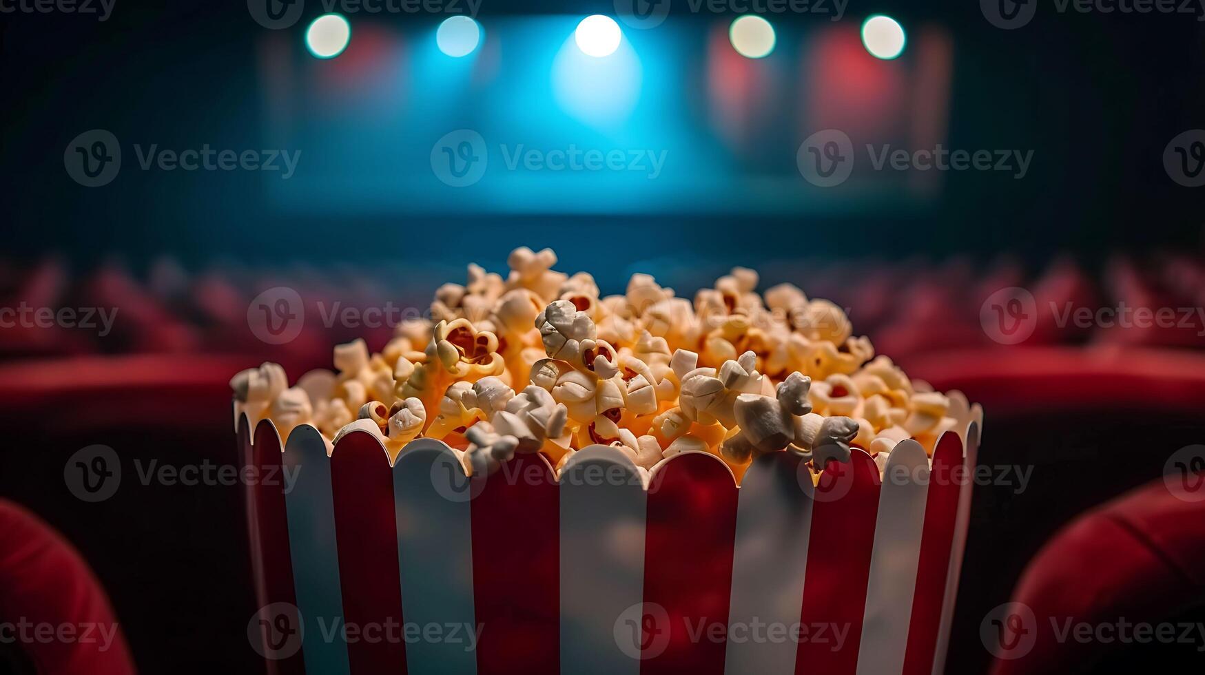 Popcorn in a red and white striped bucket on a red chair photo