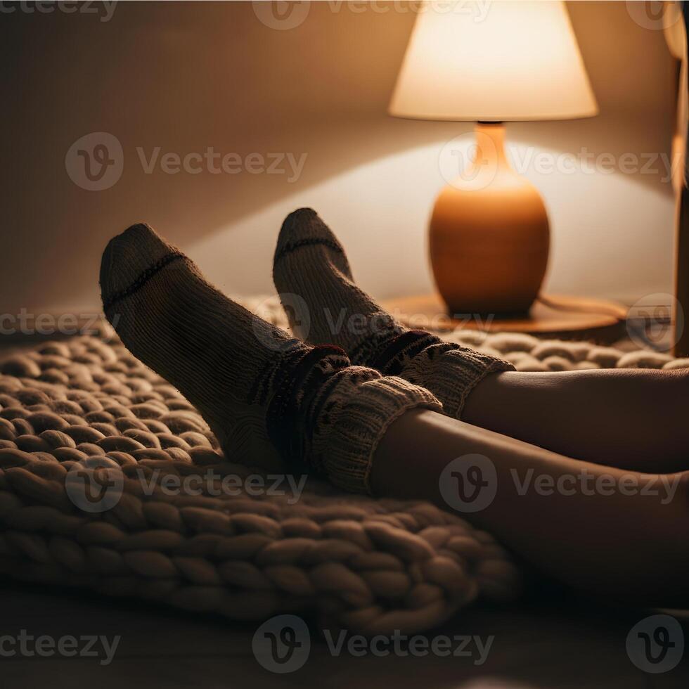 Cozy winter evening resting with patterned wool socks on thick knitted rug warm lamp light indoors photo