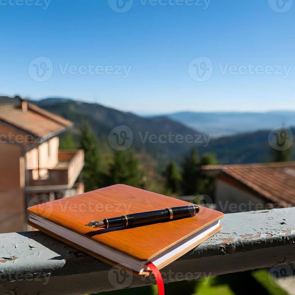 Open journal with fountain pen on a balcony railing overlooking scenic mountains during golden hour sunset photo