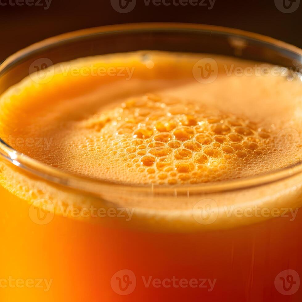 Close up of a foamy orange juice in transparent glass with soft bokeh background and fresh citrus tones photo