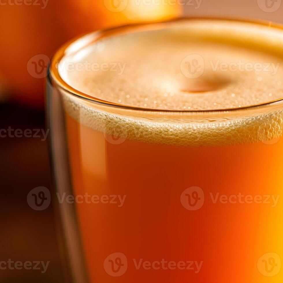 Close up foamy orange juice in a transparent glass with soft bokeh background and fresh citrus tones photo